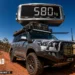 Fisheye outback track scene with a loaded 4WD under a giant floating scale reading 580 kg
