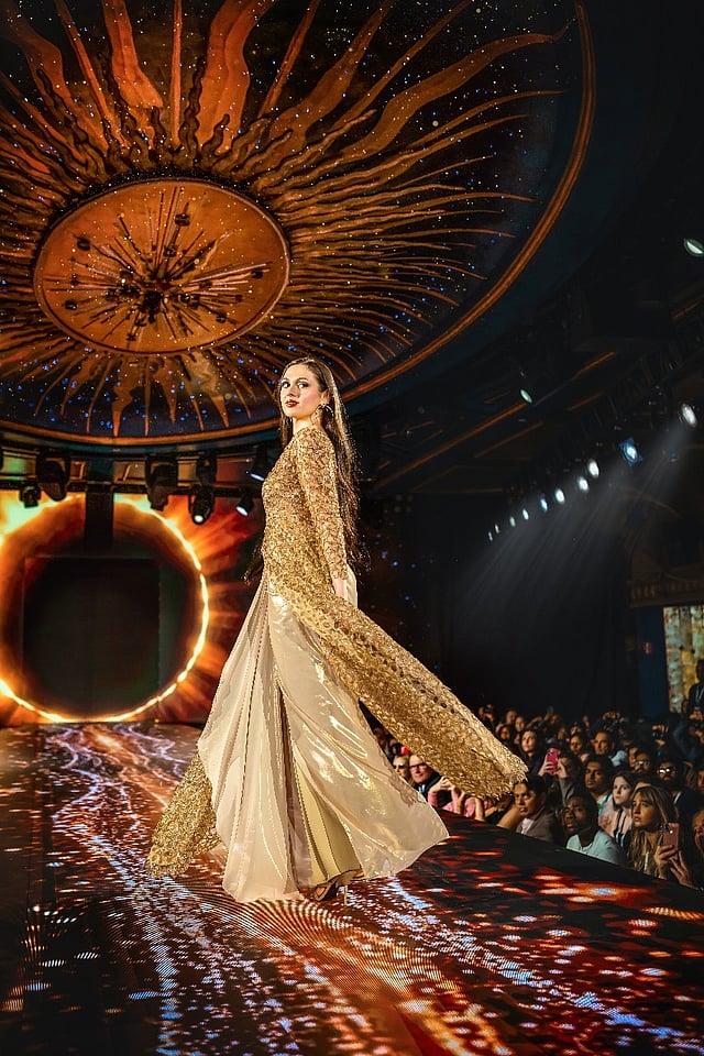 model in gold embellished gown under the illuminated sunburst dome