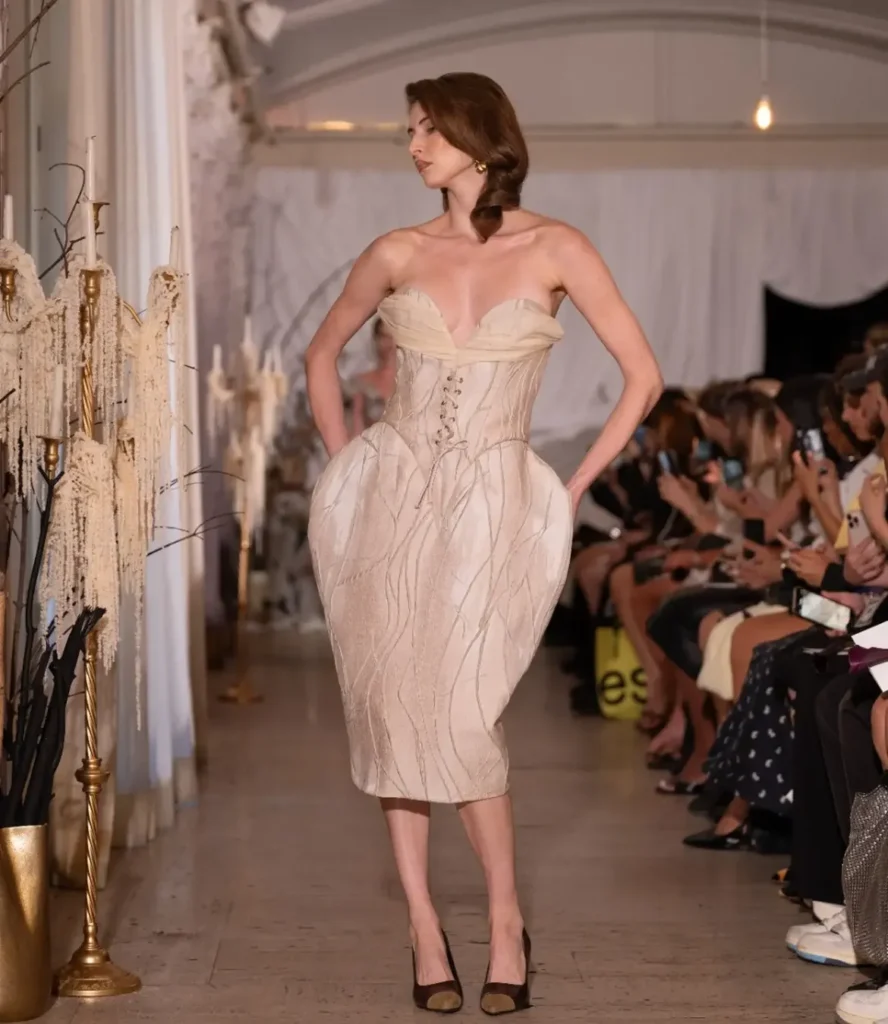 Model in a cream lace-front corset dress with sculpted pannier hips and vein-like embroidery