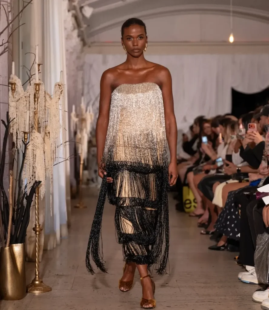 Model in a strapless beaded fringe gown fading from silver to gold to black on the Tang Chi Couture runway