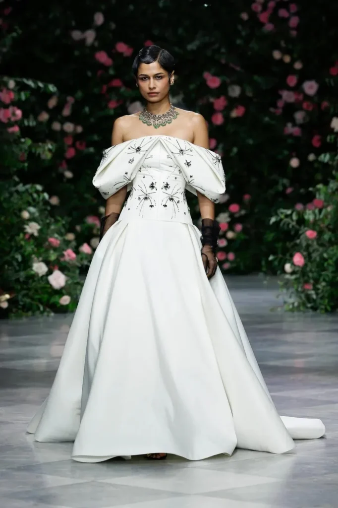 Model in an ivory off-the-shoulder ball gown with black constellation beading and an emerald choker on the Bibhu Mohapatra Spring 2027 runway