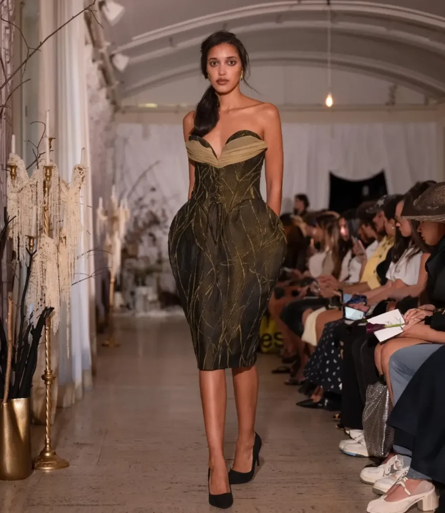 Model in an olive and gold corset dress with sculpted hips and branching gold embroidery
