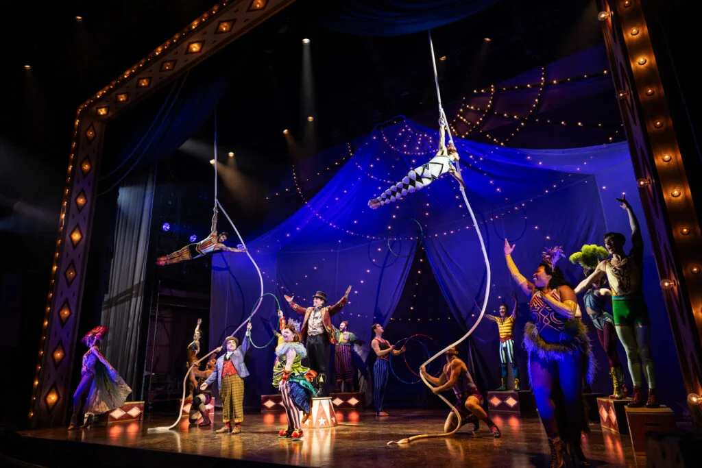 Marlena in her aerial act on the hanging rope, Jacob below reaching up toward her