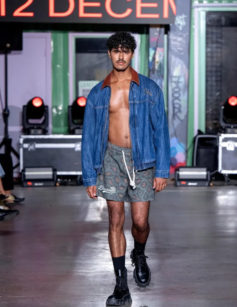 blue denim jacket with a contrast brown collar over bare chest