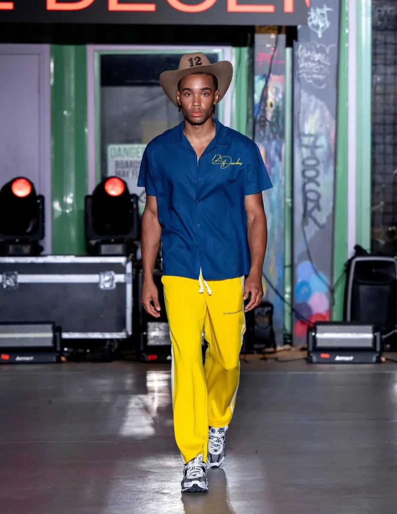 cowboy hat, blue camp shirt and bright yellow track pants with side stripes